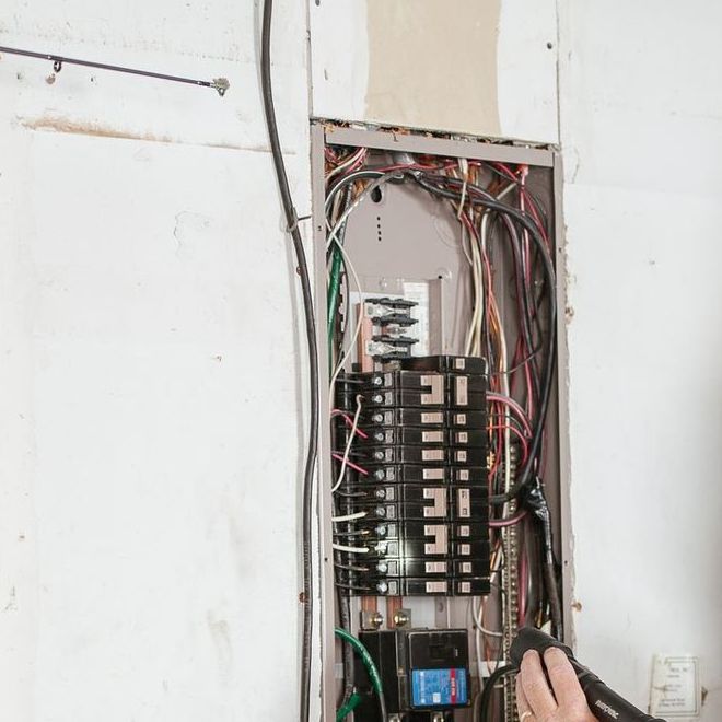 Open residential breaker panel being checked with a tester
